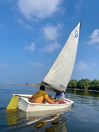 A coach demonstrating maneuvers to a student in an optimist
